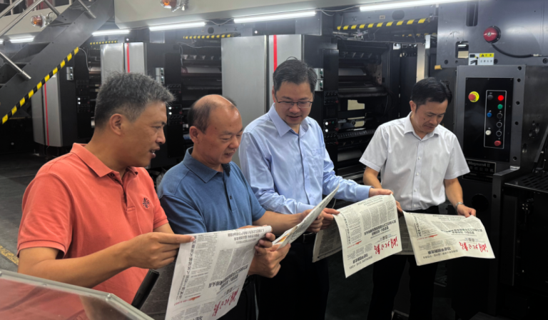 Image of 4 people looking just printed newspapers